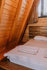 A cozy A-frame cabin bedroom with wooden interiors and natural light.