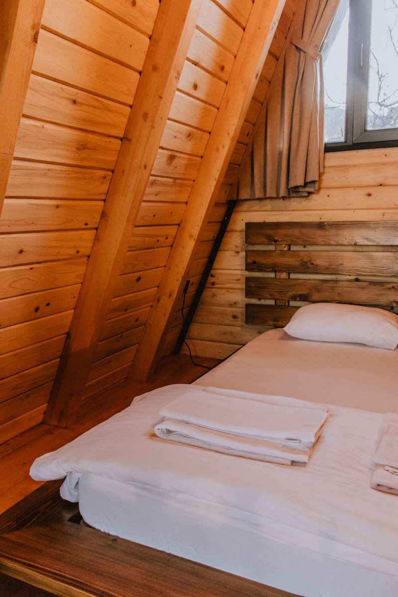 A cozy A-frame cabin bedroom with wooden interiors and natural light.